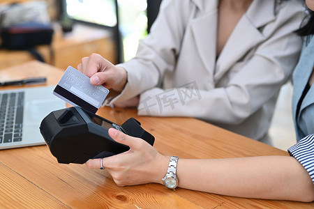 两名女性顾客通过支付终端刷信用卡的镜头。