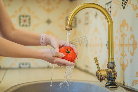 一名妇女在自来水下清洗番茄的特写镜头