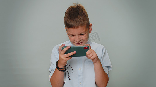 忧心忡忡、滑稽成瘾的幼儿男孩热情地在手机上玩赛车电子游戏