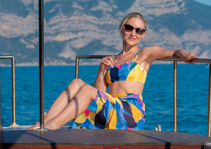 泳衣眼镜海上游艇礼服女度假美丽模特蓝色，从甲板黑发为美丽休闲海洋，旅游时尚。