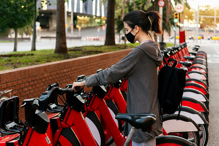 戴着防护面具的女人骑着租赁自行车