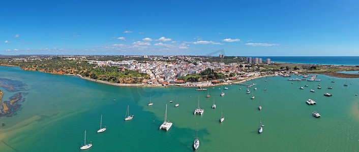 村庄之美摄影照片_葡萄牙阿尔加维阿尔沃尔村庄和港口的空中全景