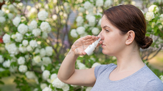白人妇女在公园散步时使用鼻喷雾剂。