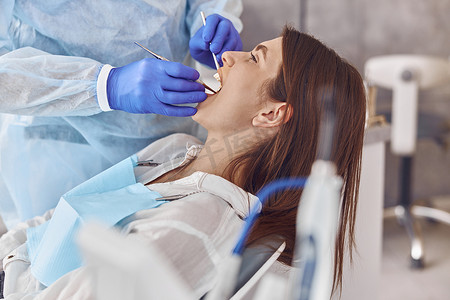 专业医生正在现代牙科柜里为快乐的白人女性做牙齿手术