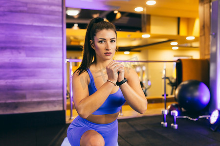 年轻漂亮的运动女性在健身房的垫子上锻炼，在镜子前，手臂摆动，蹲下，健身，瑜伽，穿着运动服
