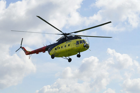 飞行中的直升机摄影照片_黄色的 MI-8 直升机在云层中飞行。