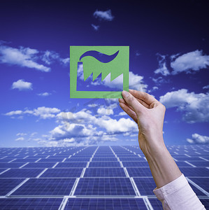可持续资源摄影照片_手握太阳能电池板上的绿色工业标志