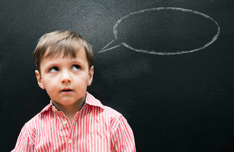 小男孩找到摄影照片_帮助你的孩子找到他的声音......一个小男孩站在黑板前，黑板上画着一个讲话泡泡。