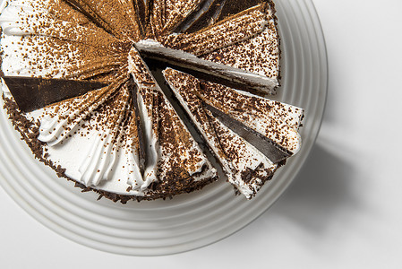 水乳摄影照片_蛋糕用巧克力，撒上巧克力片，放在白色背景的托盘上，上面有切好的碎片。