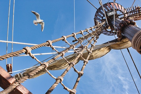 一艘老式帆船的索具和桅杆，海鸥在蓝天上飞翔