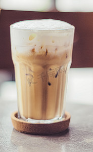 将冰咖啡放入透明高脚玻璃杯中，上面放上牛奶或奶油