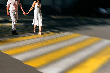 行人水墨摄影照片_白人夫妇手牵着手穿过城市十字路口，具有运动模糊效果