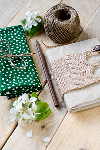 米色毛衣针织的旧复古记事本、粗纱、布料、梨花、铅笔躺在未上漆的木质背景上。