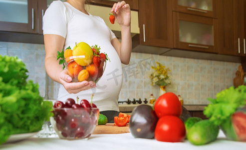孕妇摄影照片_孕妇吃蔬菜和水果。