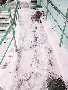 无障碍摄影照片_带金属栏杆的现代坡道，可供残疾人无障碍移动，坡道覆盖着雪，垂直照片