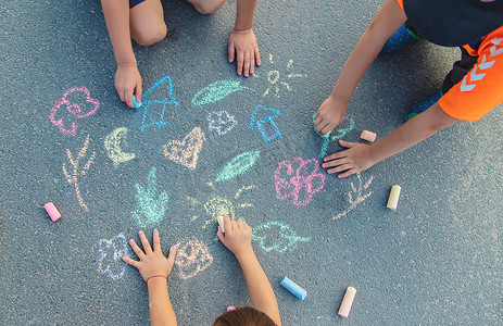 儿童用粉笔在沥青上画画。