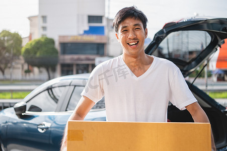 快乐的亚洲男人正在通过私家车向顾客运送纸板箱。
