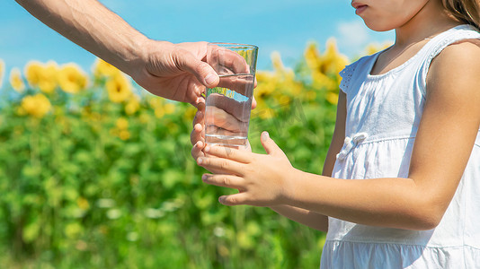 水春天摄影照片_父亲在田野的背景下给孩子喝水。