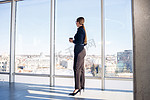 自信的女商人老板站在现代办公室或酒店的窗户里，欣赏大城市的景色，女领导，企业主思考未来的成功，规划新的机会，