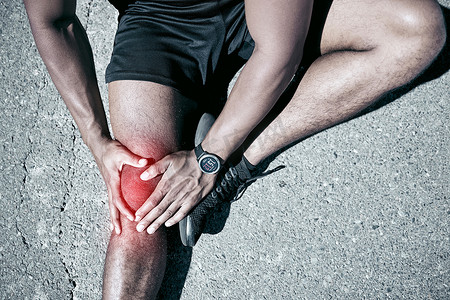 特写适合混血男子在户外锻炼时抱着膝盖疼痛。
