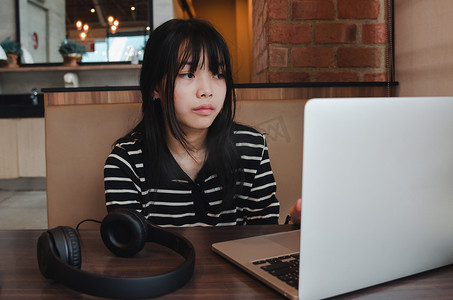 女孩使用电脑笔记本电脑看电影或用耳机和数字互联网通信社交网络听音乐。