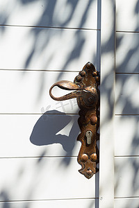 传统的地中海背景由白色木门的建筑细节组成，配有黄铜门把手和橄榄树阴影。