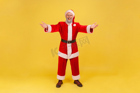 你不知道的那些事摄影照片_全长快乐的老人，留着灰胡子，穿着圣诞老人服装，举手拥抱，欢迎和微笑，对见面感到高兴。