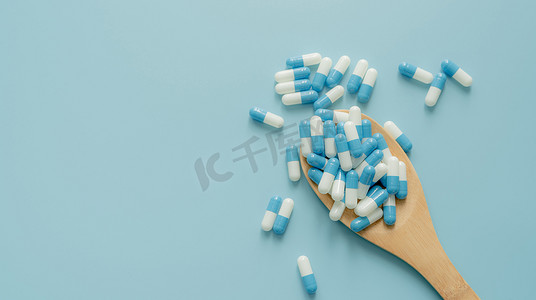木勺和蓝色背景上的蓝白色抗生素胶囊药丸。