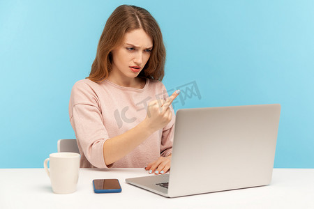 王八摄影照片_在蓝色背景上使用笔记本电脑的情感年轻女子。