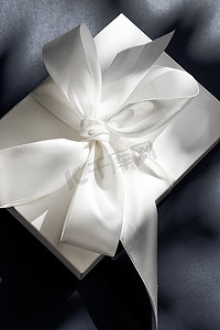 黑色背景上带丝带和蝴蝶结的豪华假日白色礼盒、豪华婚礼或生日礼物