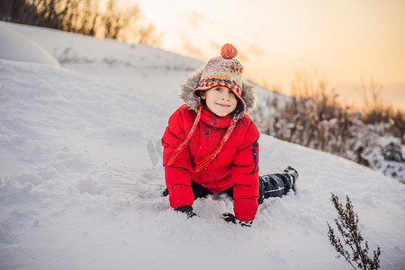 下雪玩耍摄影照片_穿着红色时尚衣服的男孩在户外玩耍。