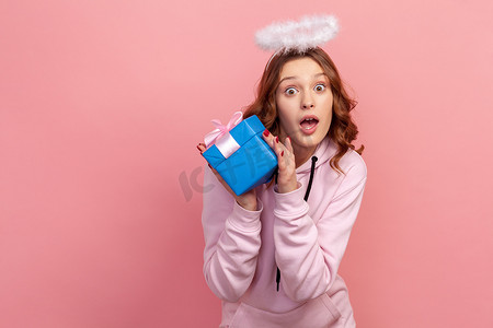 身穿连帽衫,头戴光环的卷发少女惊讶的肖像,镜头前展示着包装好的礼盒