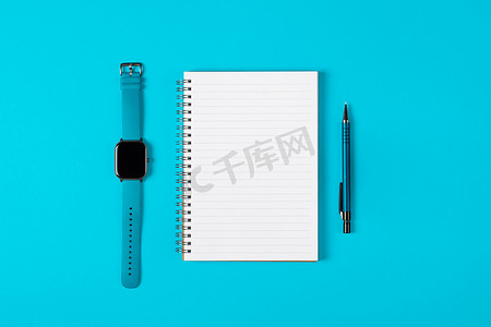 记事本、手表、钢笔隔离在浅蓝色背景上。
