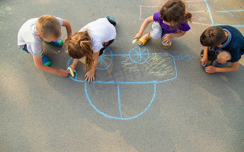 孩子们用粉笔在人行道上画一辆汽车。