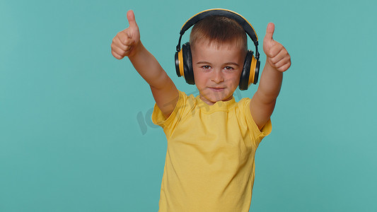 小孩音乐摄影照片_快乐的小小孩男孩通过耳机听音乐，跳舞迪斯科，愚弄，玩得开心