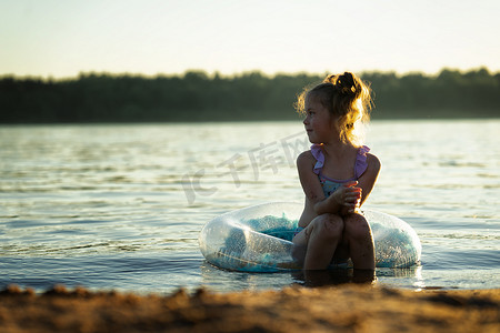 海滩上的小女孩坐在充气环上的水中