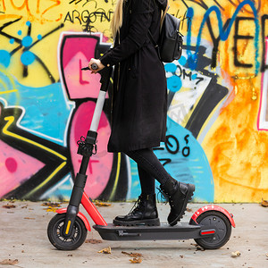 秋季，时尚少女在城市环境中骑着公共租赁电动滑板车。