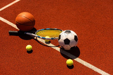一组黑色背景的运动器材，包括网球、篮球、足球和拳击器材，背景有复制空间
