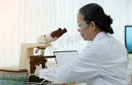药物实验摄影照片_一位在研究实验室工作的医生，从事药物实验的科学高级女性。