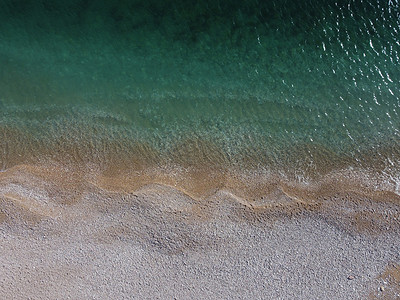 海洋模糊摄影照片_从空中俯瞰蔚蓝的大海和粉红色的鹅卵石海滩。