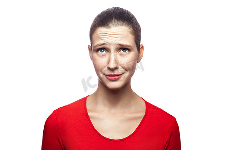 穿着红色T恤、有雀斑的悲伤不幸的女人的肖像。
