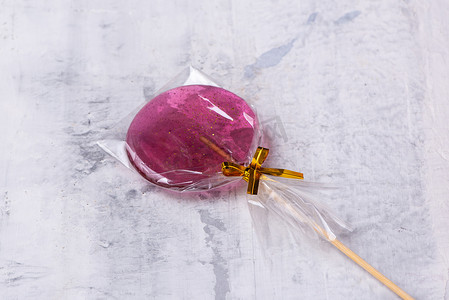 棒棒糖粉色背景摄影照片_带纹理的背景上的粉红色棒棒糖