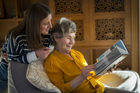 老人病摄影照片_老妇人和她的孙女看着家庭照片。