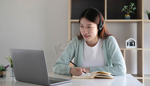 亚洲女学生在家里客厅的电脑上与老师进行视频会议电子学习。