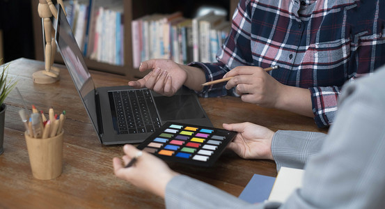 设计师图形创意与同事一起使用图形平板电脑和办公桌上的手写笔进行着色
