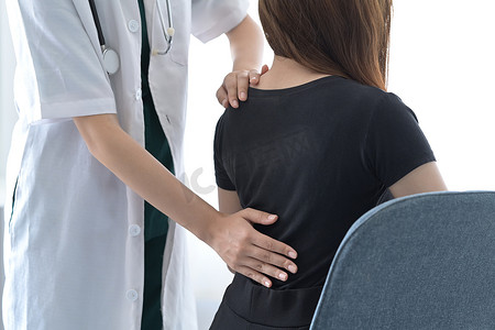 物理治疗师检查背部受伤的女性患者。