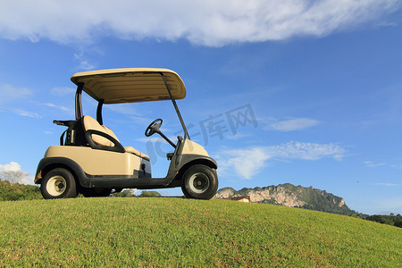 在道路上的高尔夫球车、漂亮的绿草和蓝天背景