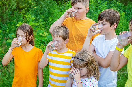 家庭喝水摄影照片_孩子们一起在外面喝水。