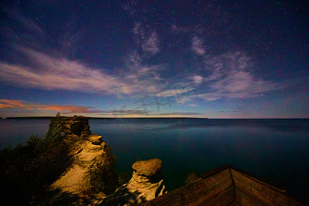 星空云彩摄影照片_柔软的粉红色云彩和俯瞰密歇根湖的悬崖上的星空
