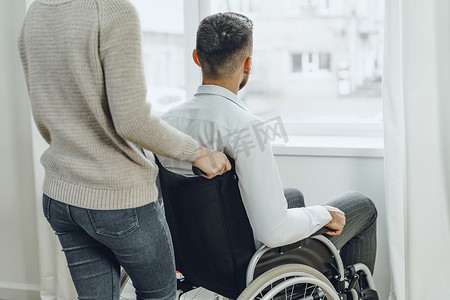 残疾人摄影照片_在家照顾坐轮椅的残疾人的妇女